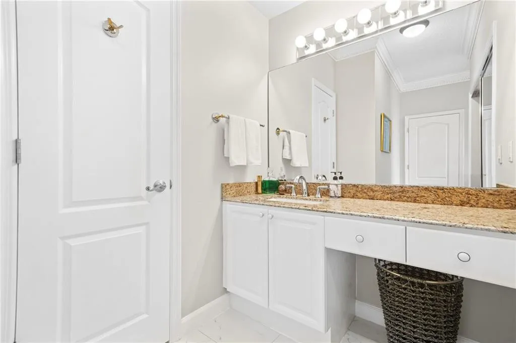 Bathroom with baseboards, marble finish floors, crown molding, and vanity