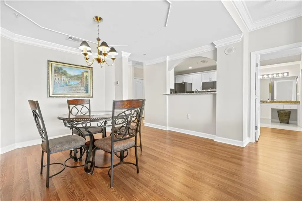 Dining area with light wood-type flooring, a chandelier, crown molding, baseboards, and arched walkways