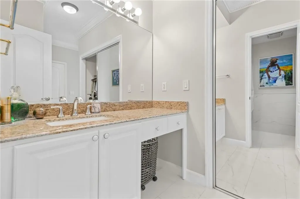 Bathroom featuring ornamental molding, marble look tile flooring, baseboards, and vanity