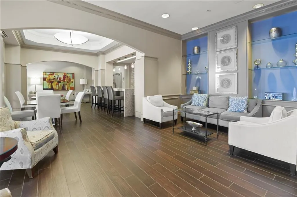 Living room featuring arched walkways, ornamental molding, decorative columns, wood finished floors, and recessed lighting