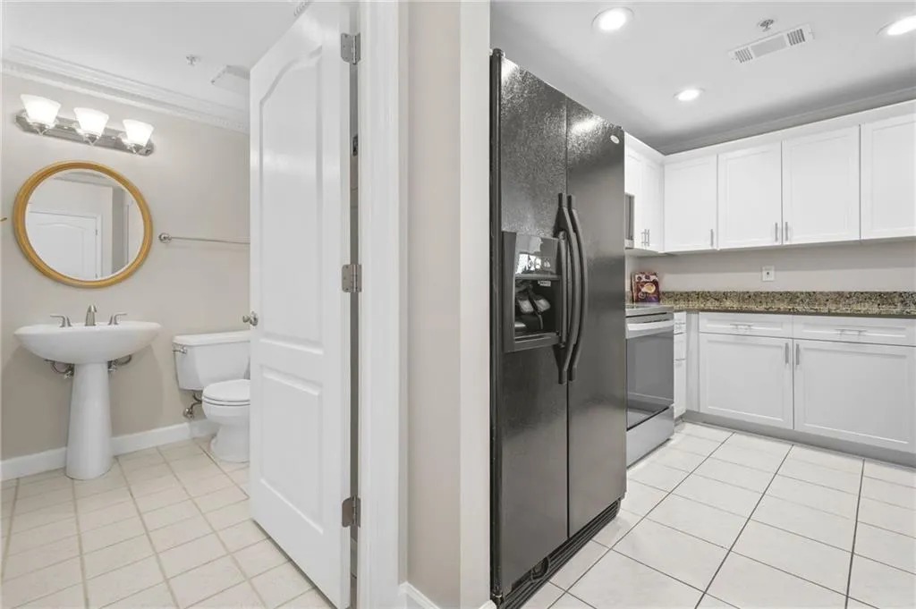 Kitchen featuring black fridge with ice dispenser, light tile patterned flooring, crown molding, white cabinets, and stainless steel electric stove