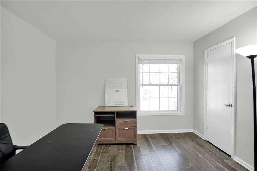 Unfurnished office with baseboards and dark wood-style flooring