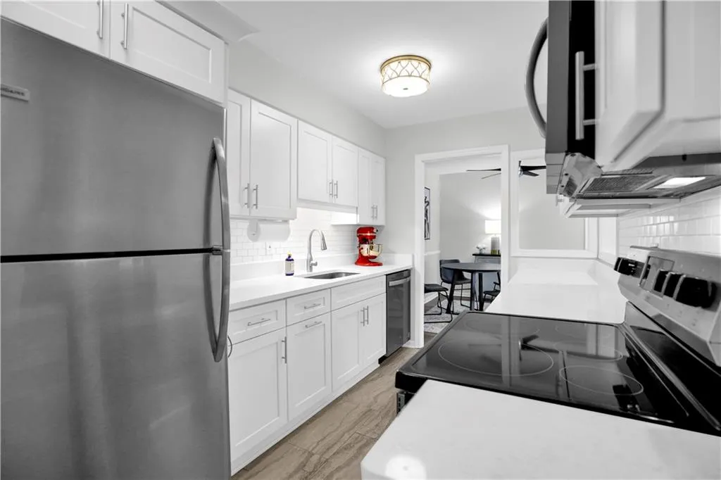 Kitchen with stainless steel appliances, white cabinets, tasteful backsplash, a ceiling fan, and light stone countertops