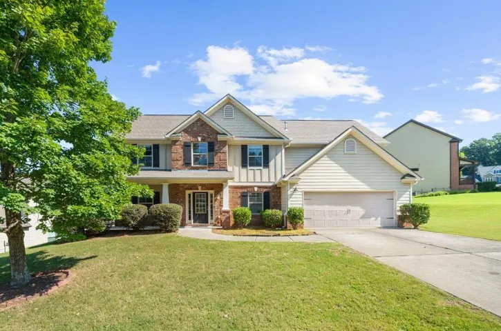 Two-story residence featuring a brick and siding exterior, front entry porch, and an attached two-car garage