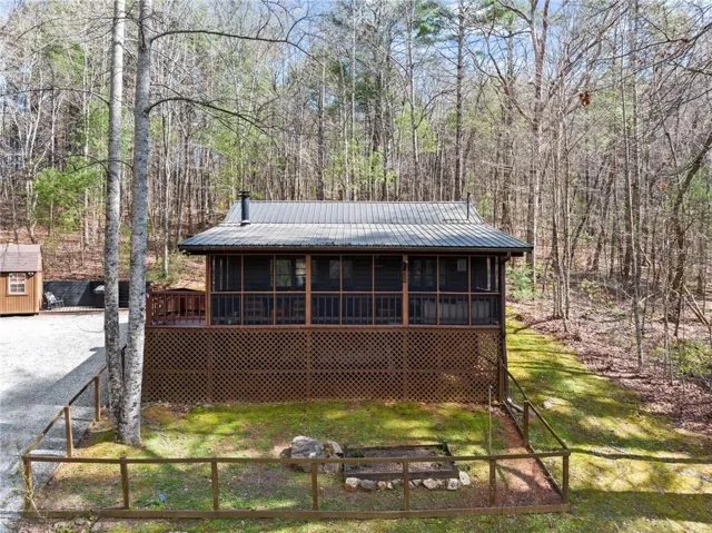 View of front of home featuring a wooden deck, grill area, screened porch, front yard fenced and a metal roof
