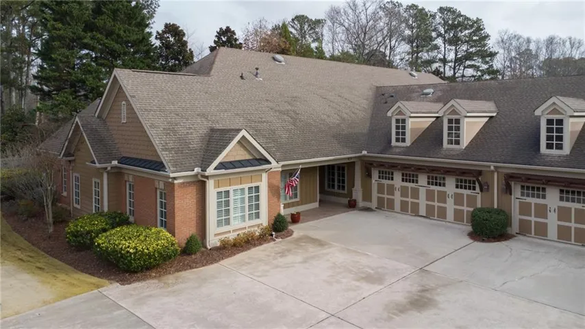 Cape cod home featuring concrete driveway, a shingled roof, and board and batten siding