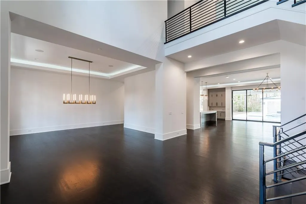 Unfurnished living room featuring a chandelier, dark wood-style floors, baseboards, a raised ceiling, and recessed lighting