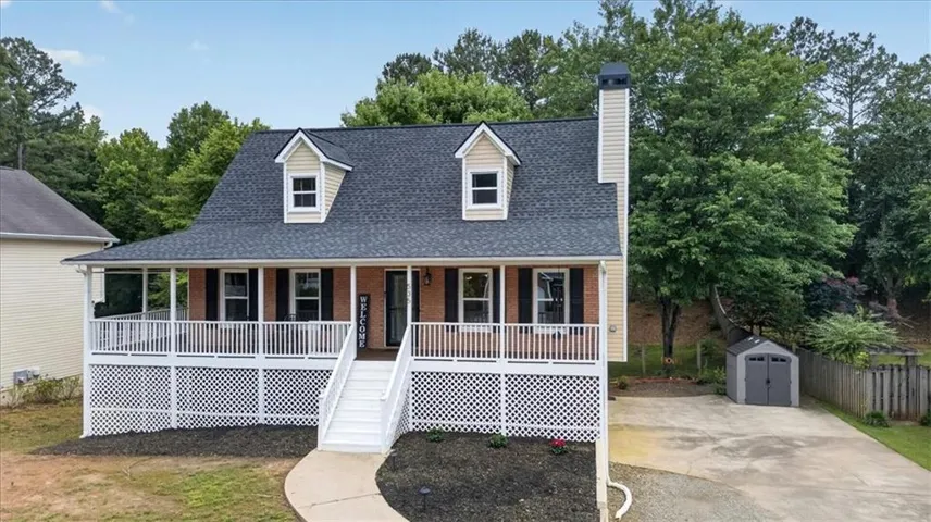 Two-story residence featuring a covered front porch, dormer windows, a prominent chimney, and a detached storage shed