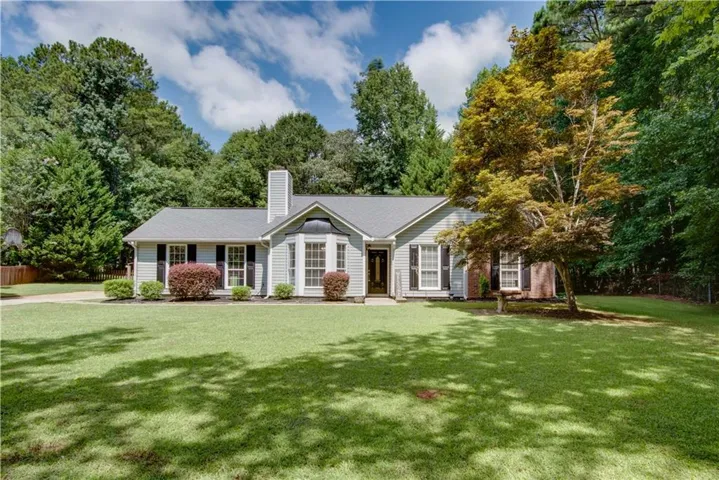 Ranch-style residence featuring light-colored siding, a dark roof, and a prominent bay window