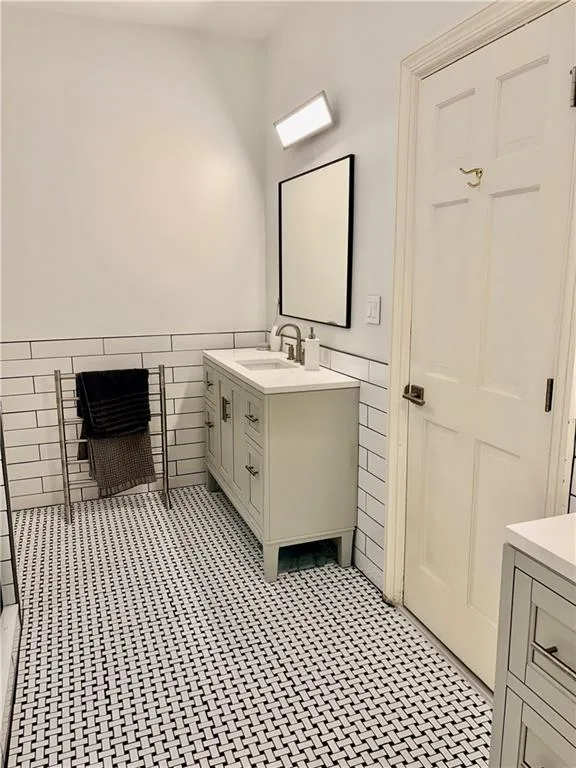 White subway tile wainscoting, white walls, and basketweave tile flooring