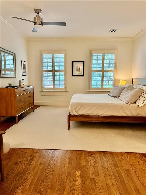 Hardwood flooring, crown molding, dual windows with plantation shutters, and a ceiling fan