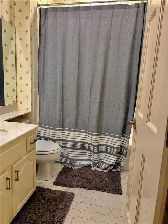 3rd Bedroom/Office Bathroom with White hexagonal tile flooring, vanity with cream-painted cabinetry, and a built-in tub with shower