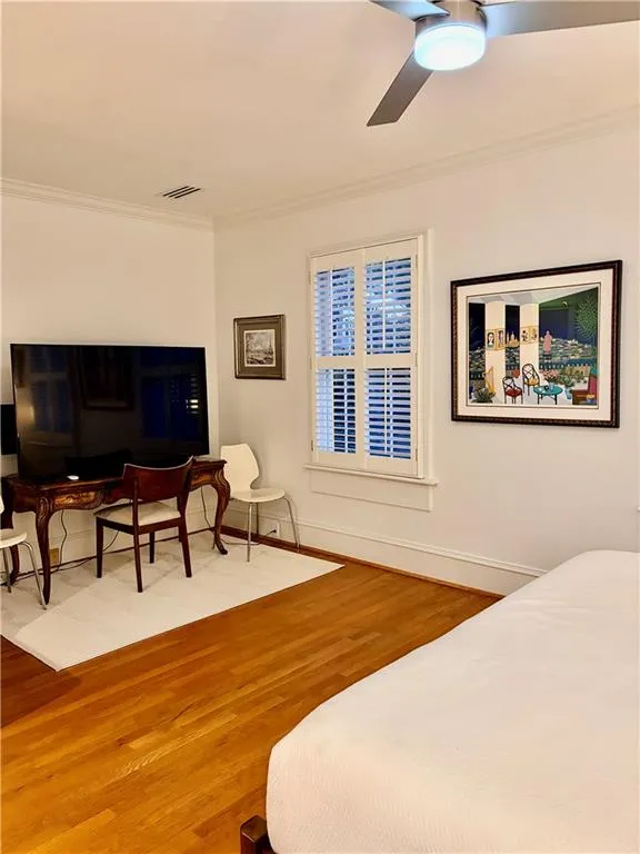 2nd Bedroom Hardwood flooring, crown molding, ceiling fan with integrated lighting, and window with plantation shutters