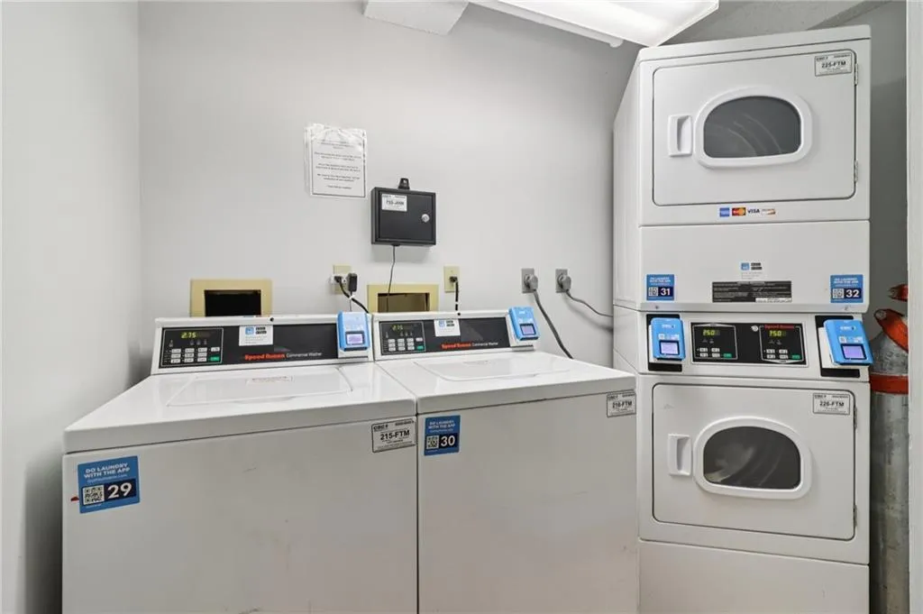 Shared laundry room with stacked washer and clothes dryer and washer and clothes dryer