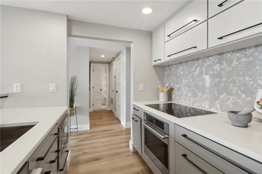 Kitchen featuring stainless steel oven, black electric cooktop, light countertops, light wood finished floors, and gray cabinets