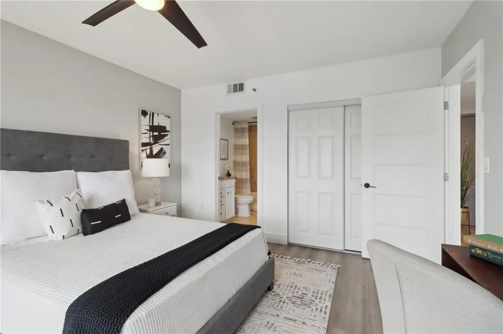 Bedroom featuring wood finished floors, a closet, connected bathroom, and ceiling fan