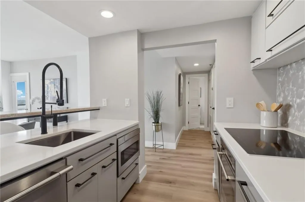 Kitchen with stainless steel appliances, a sink, light countertops, white cabinetry, and light wood finished floors