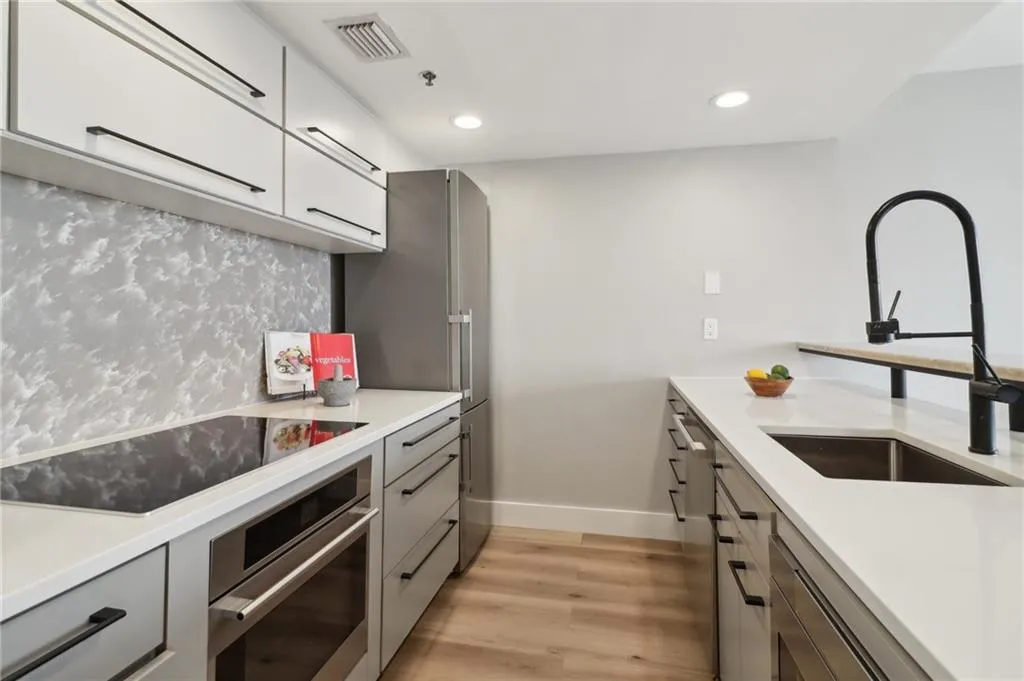 Kitchen featuring appliances with stainless steel finishes, a sink, light wood-type flooring, gray cabinetry, and recessed lighting