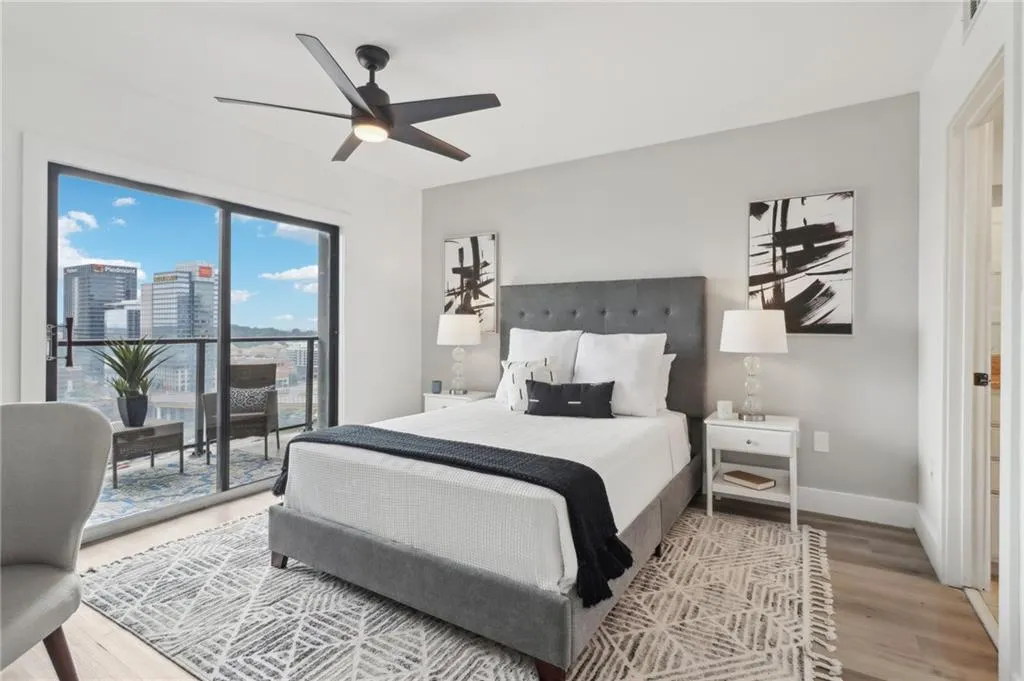 Bedroom featuring access to outside, light wood-style floors, baseboards, ceiling fan, and a view of city