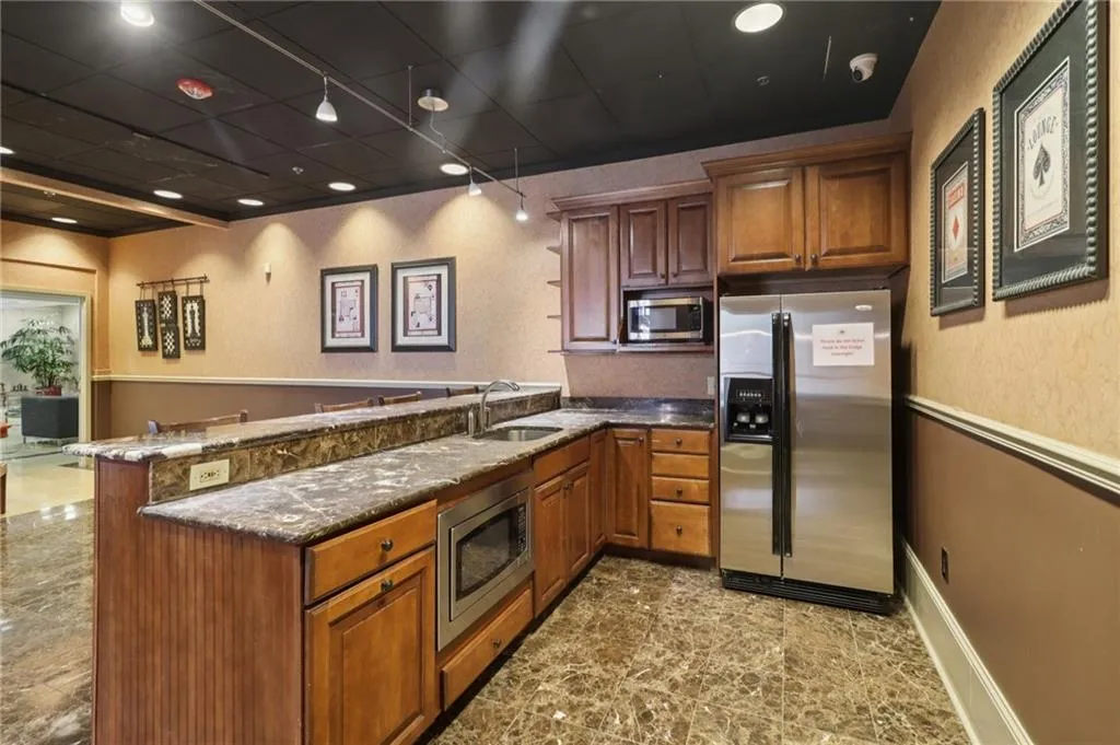 Kitchen with stainless steel appliances, a sink, a peninsula, and brown cabinets