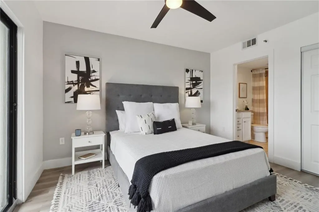 Bedroom with light wood-style flooring, ensuite bathroom, baseboards, and a ceiling fan