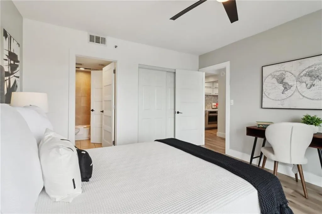 Bedroom featuring light wood finished floors, a closet, ensuite bathroom, a ceiling fan, and baseboards