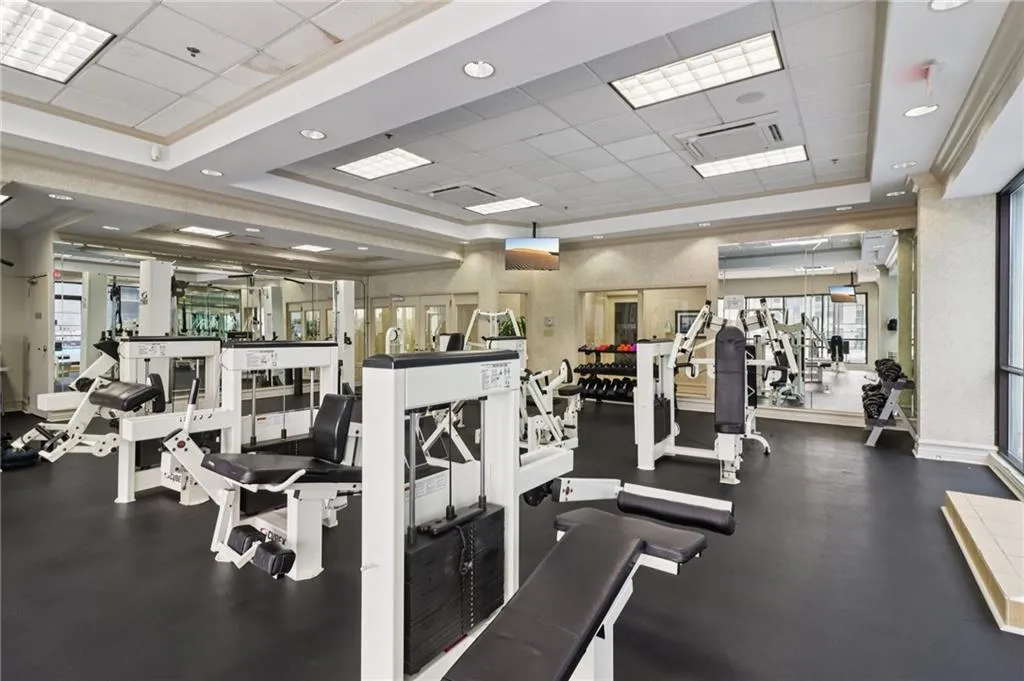 Workout area with a paneled ceiling, a raised ceiling, and recessed lighting