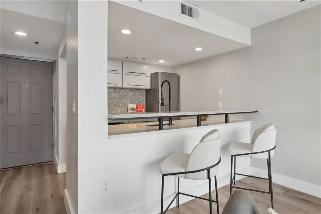 Kitchen with decorative backsplash, light wood-type flooring, recessed lighting, baseboards, and a breakfast bar area