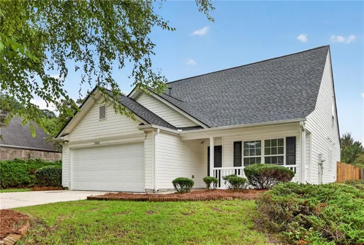 White siding exterior with a dark shingle roof, attached two-car garage, covered entry porch, and front landscaping