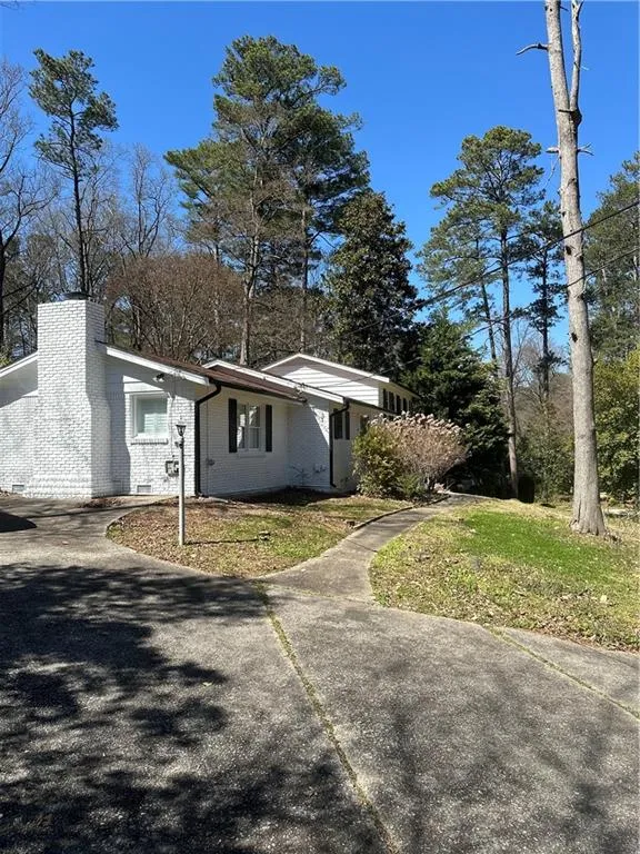 View of side of property with a yard, brick siding, concrete driveway, and a chimney