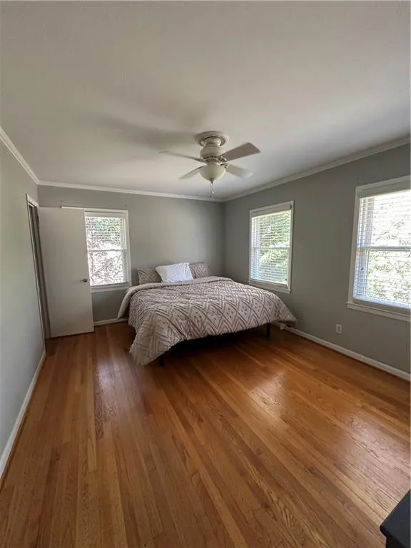 Bedroom featuring multiple windows, wood finished floors, and ornamental molding
