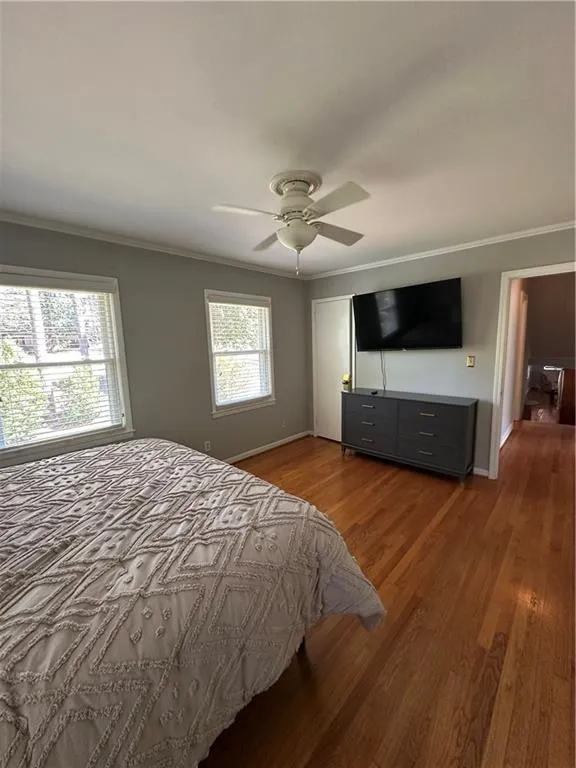 Bedroom with wood finished floors, baseboards, and ornamental molding