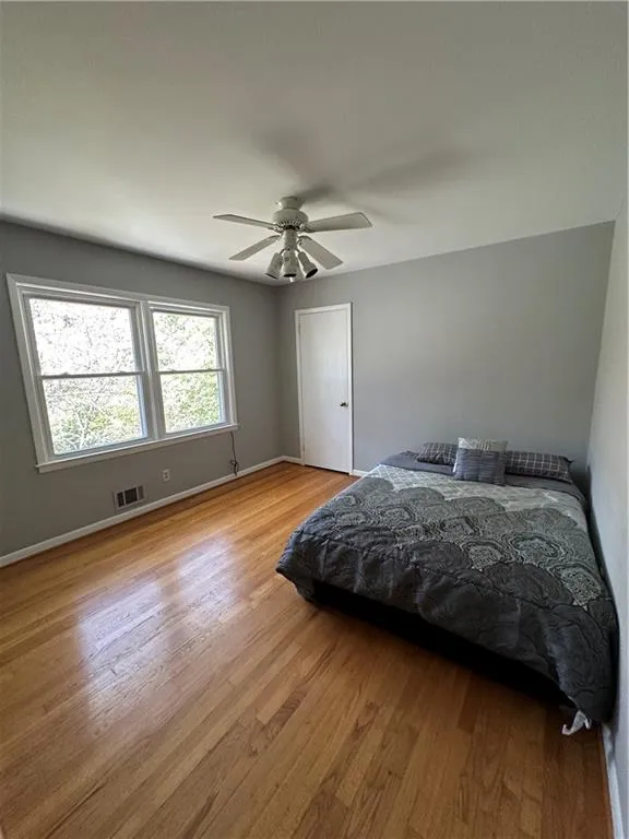 Bedroom featuring a ceiling fan, baseboards, visible vents, and light wood finished floors