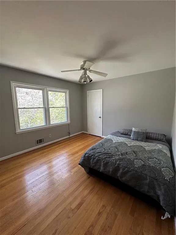 Bedroom with visible vents, a ceiling fan, baseboards, and wood finished floors