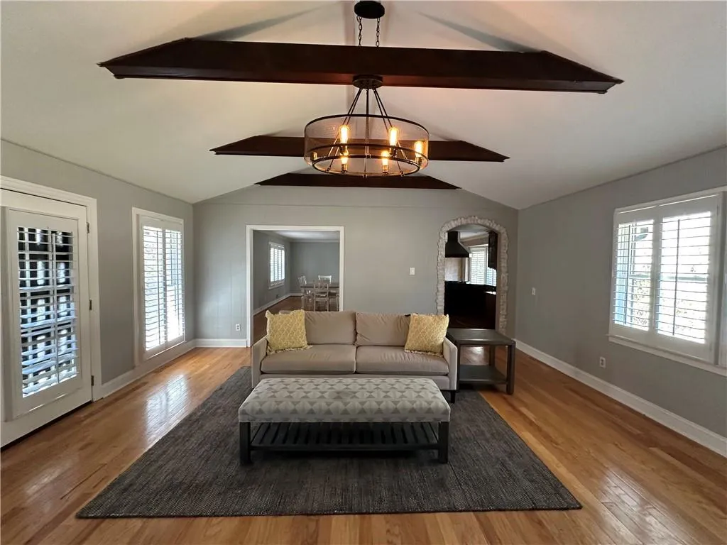 Living area featuring a wealth of natural light, a chandelier, and vaulted ceiling with beams