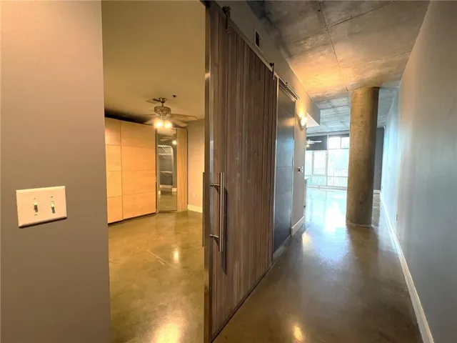 Exposed concrete ceiling, polished concrete flooring, industrial-style column, wood-finish sliding barn door, on Bedroom