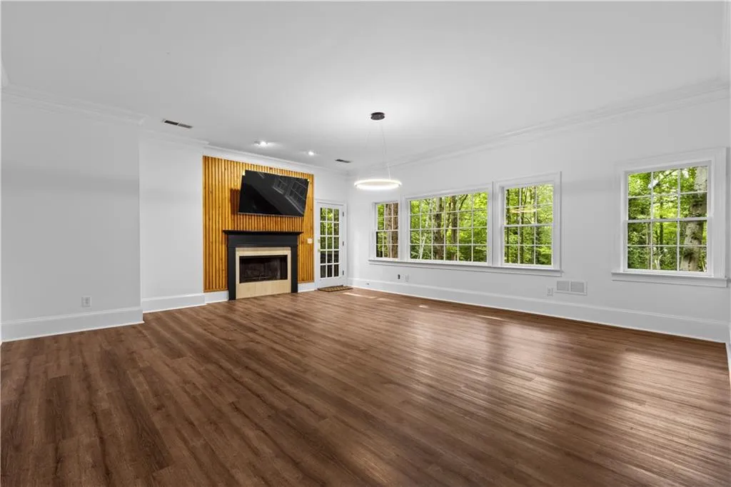 Unfurnished living room with crown molding, a large fireplace, and dark wood-style flooring