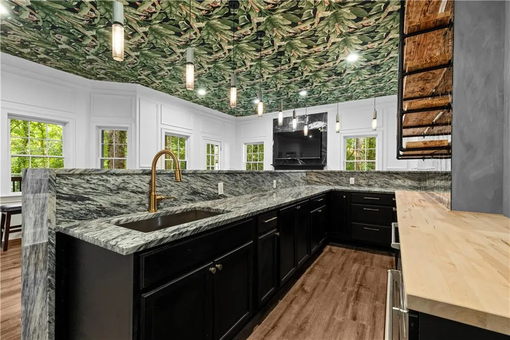 Kitchen featuring dark cabinets, hanging light fixtures, butcher block countertops, and dark wood-type flooring