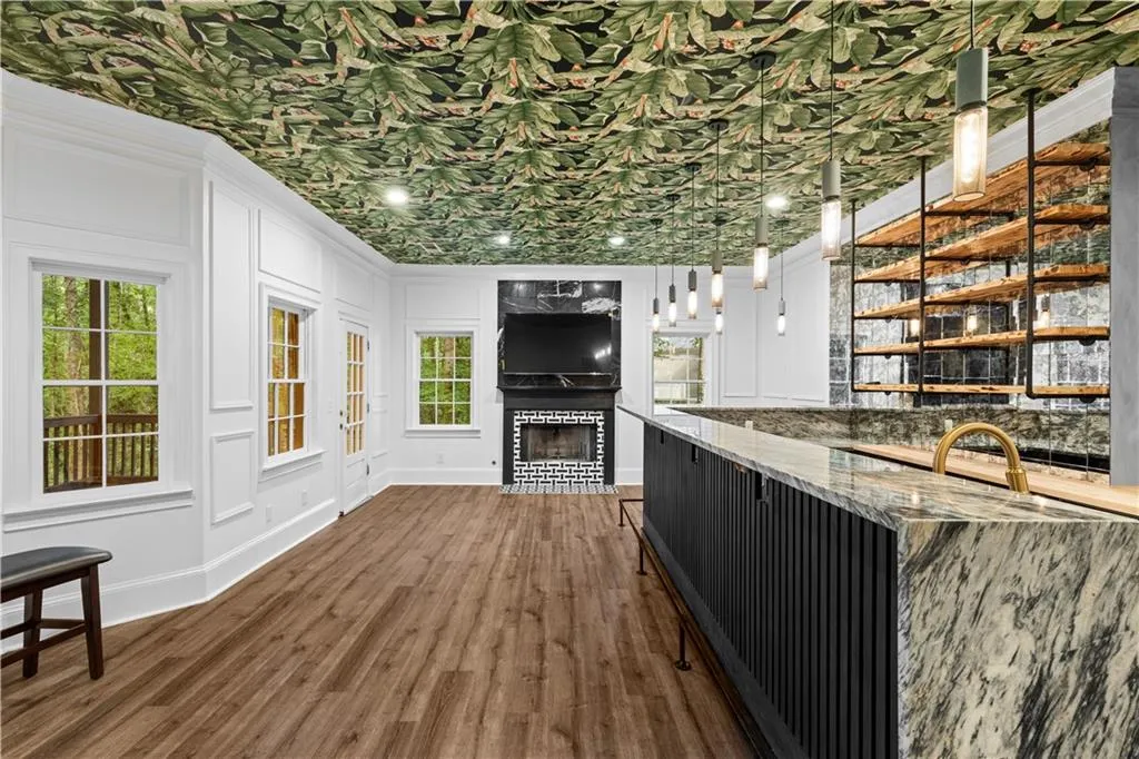 Bar featuring hanging light fixtures, dark wood-style floors, dark stone countertops, open shelves, and a decorative wall