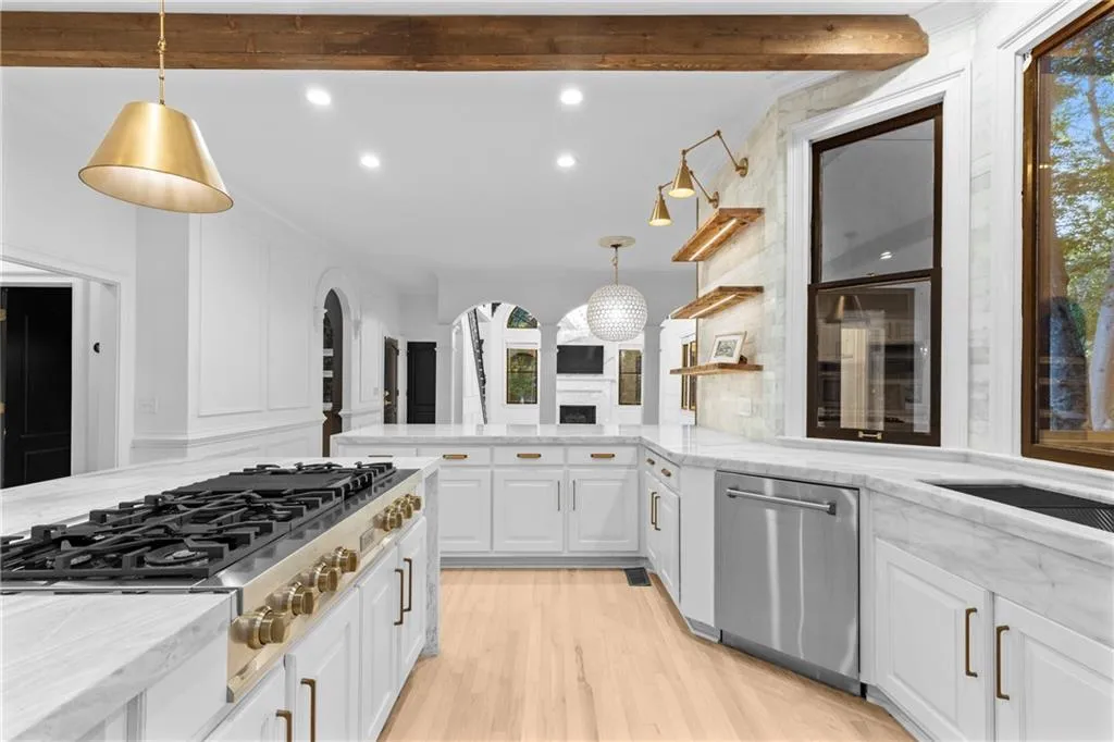 Kitchen featuring decorative light fixtures, open shelves, light stone countertops, stainless steel appliances, and recessed lighting