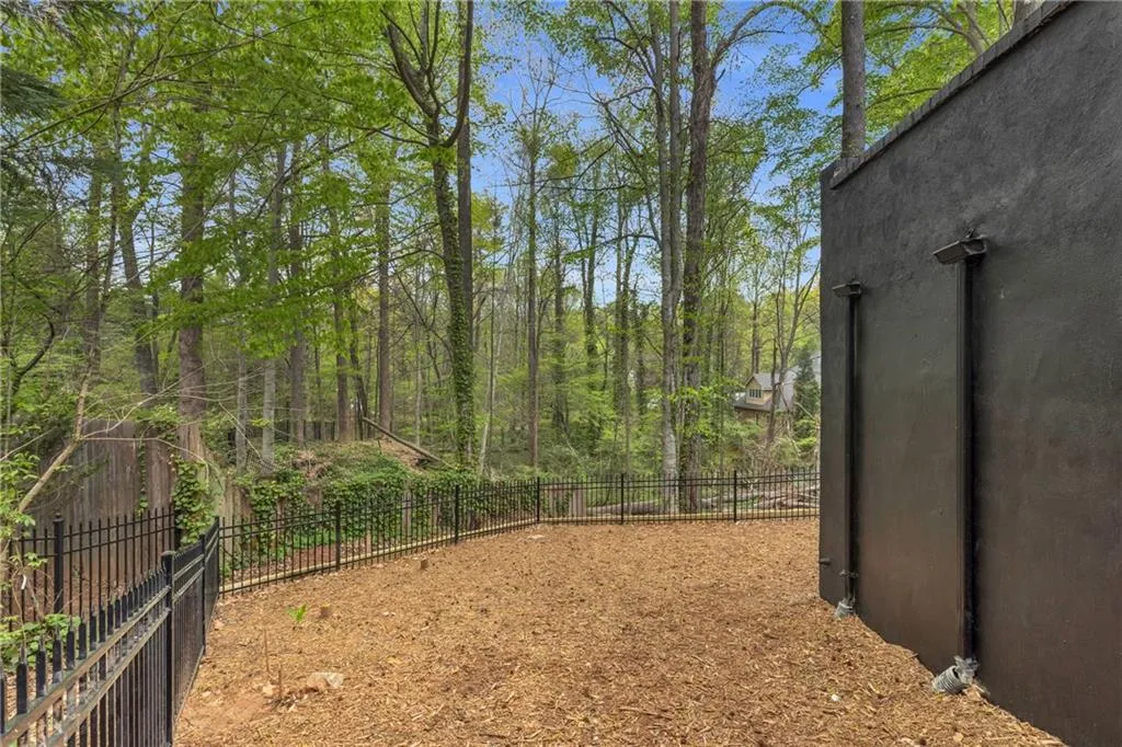 Fenced backyard featuring a wooded view
