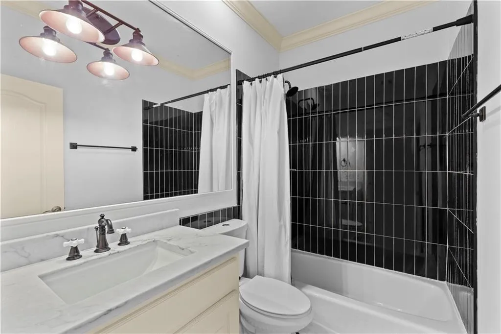 Bathroom with vanity, shower / bathtub combination with curtain, and crown molding