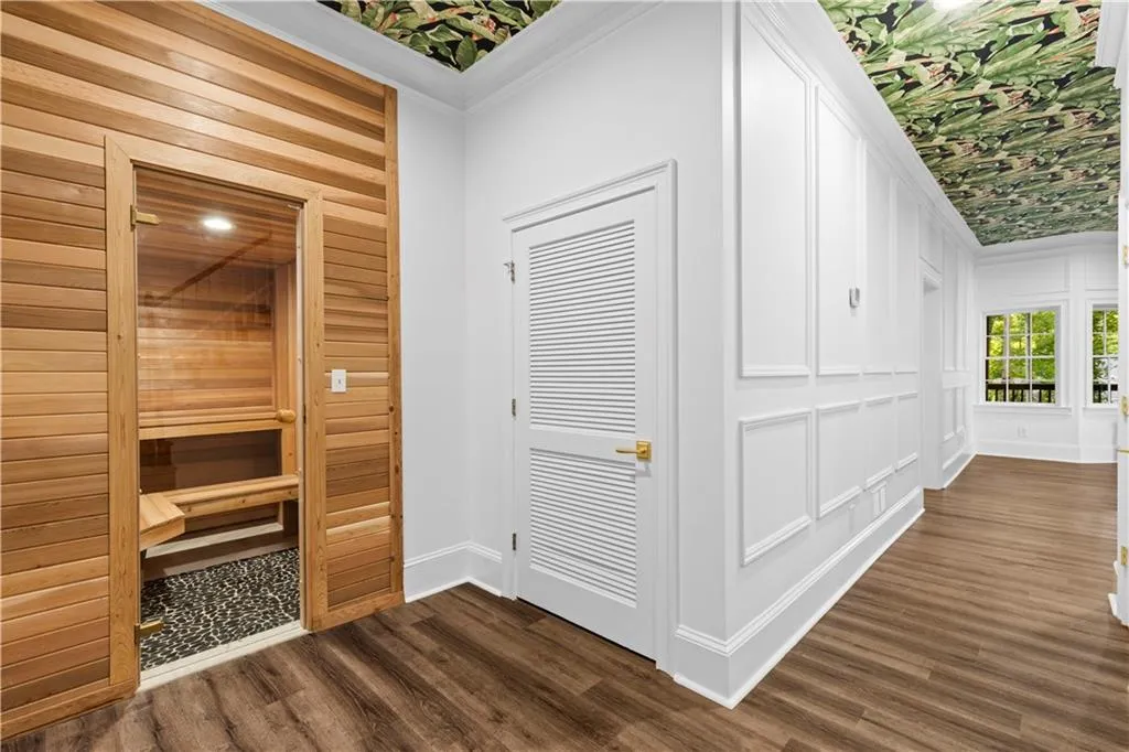 Hall with a sauna / steam room, dark wood-style floors, ornamental molding, and a decorative wall