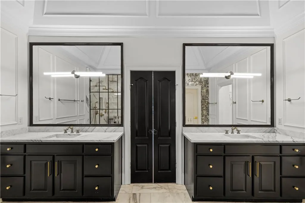 Full bathroom featuring two vanities and light marble finish floors
