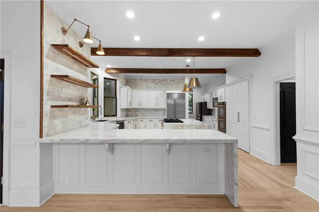 Kitchen featuring open shelves, white cabinetry, a peninsula, light stone counters, and decorative backsplash