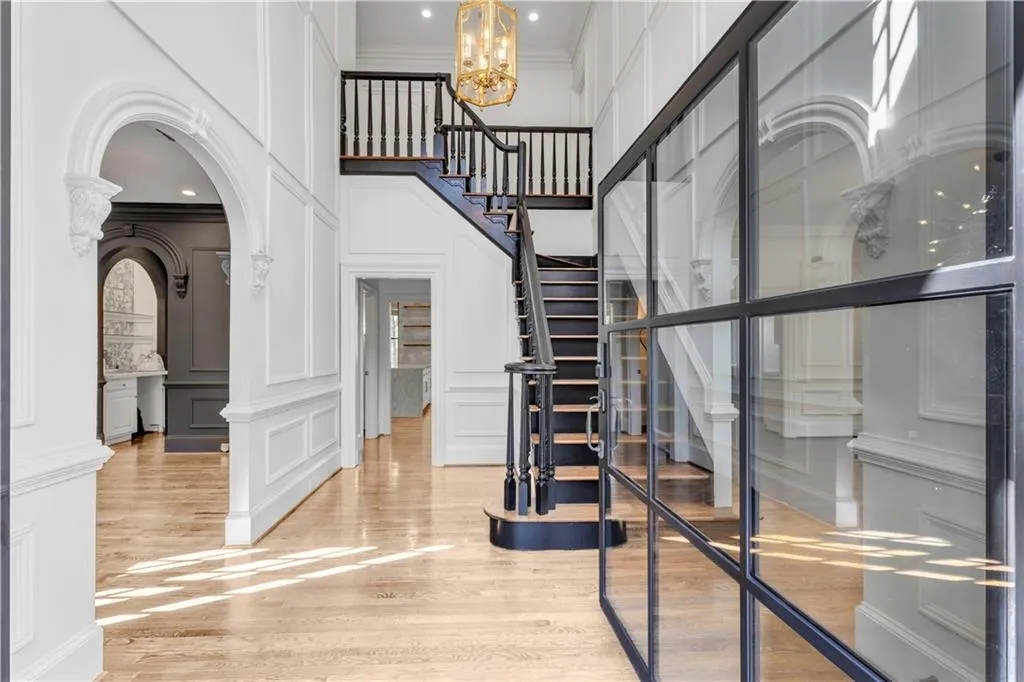 Foyer entrance featuring a decorative wall, arched walkways, a chandelier, ornamental molding, and light wood-type flooring