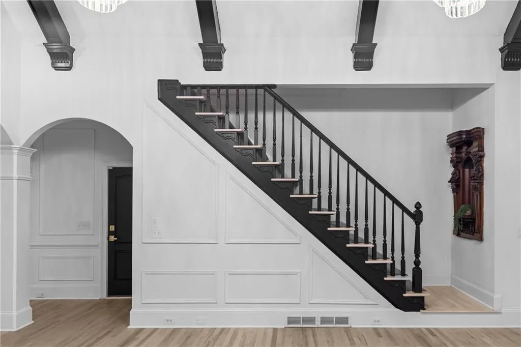 Stairway featuring wood finished floors and arched walkways