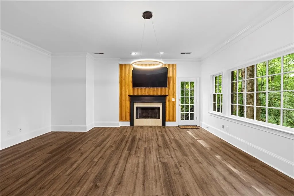 Unfurnished living room with crown molding, a large fireplace, and dark wood-style flooring
