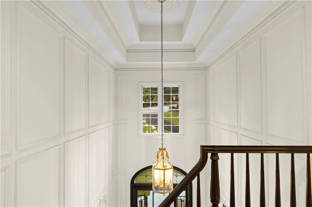 Stairway with a chandelier, a tray ceiling, and ornamental molding