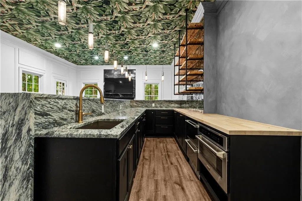 Bar area with dark cabinetry, pendant lighting, light wood finished floors, butcher block countertops, and stainless steel oven